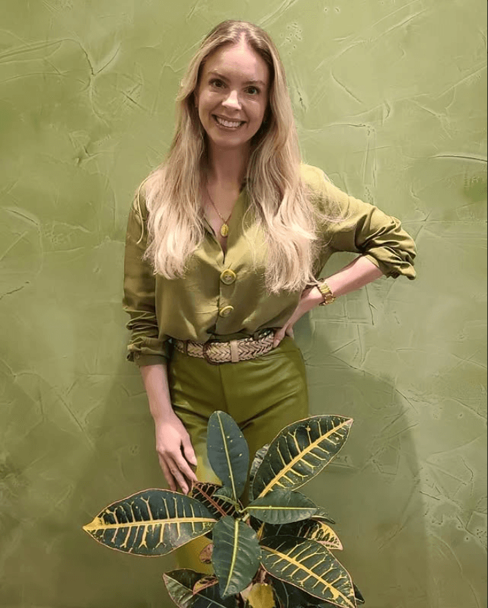 Especialista da Clínica Esthé em Curitiba, sorrindo diante da parede verde da clínica